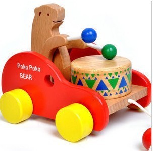 Children ages 1 to 3 years old wooden toy bear beating drum and pulling cart