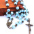 A necklace of blue pearls and rosary ornaments covered with stone crosses for who and Christian prayers