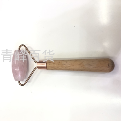 Facial massager with beech wood handle and crystal pink stone reduces edema and massages the face